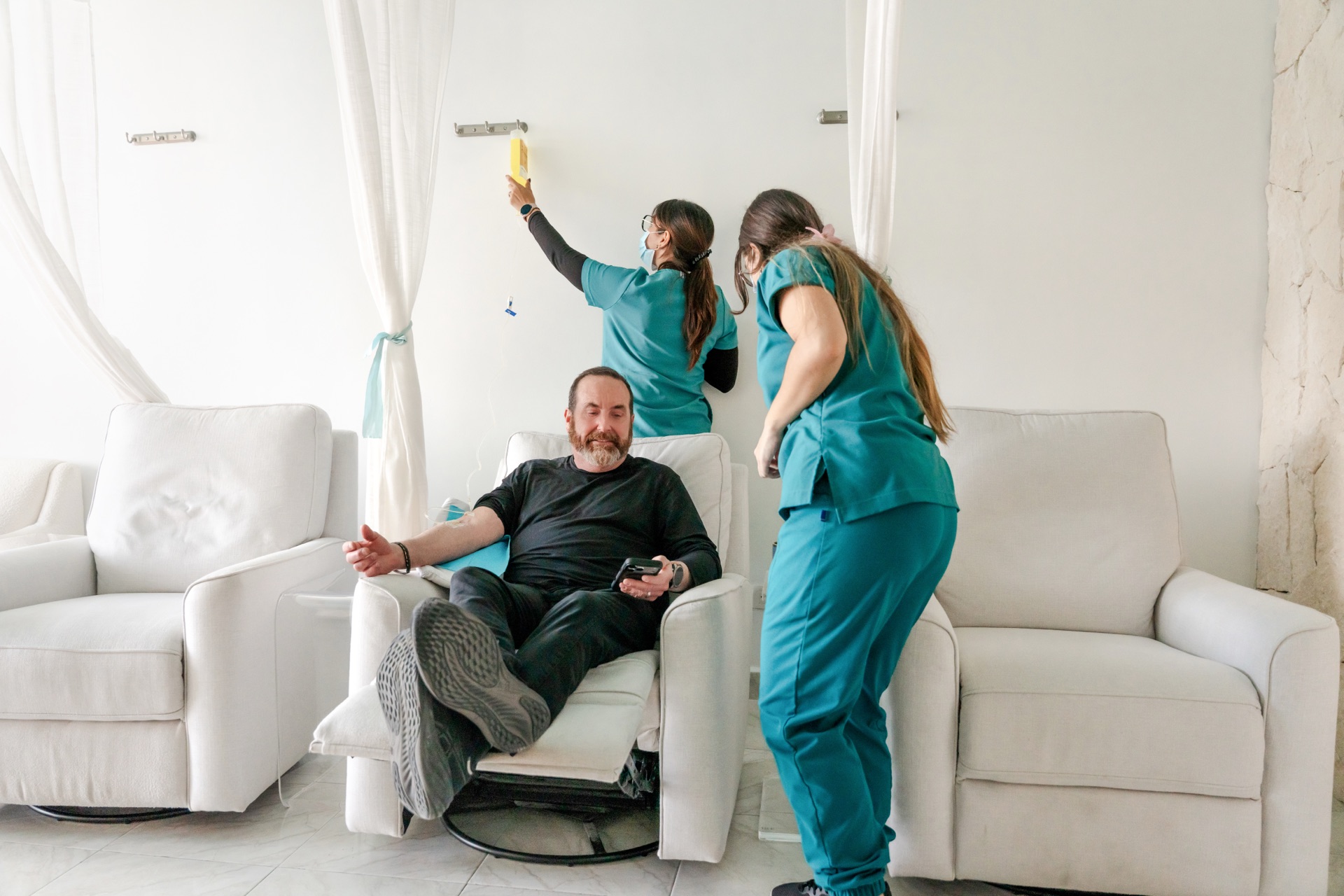 Happy male patient relaxing on a recliner while two nurses attend to him at Regeneris
